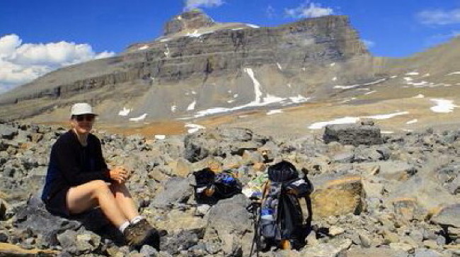 female hiker sitting on large boulder on a mountain slope female hiker sitting on large boulder on a mountain slope