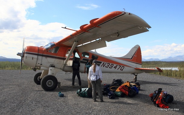Bush plane loading up backpacking gear with a female hiker amongst the camping gear