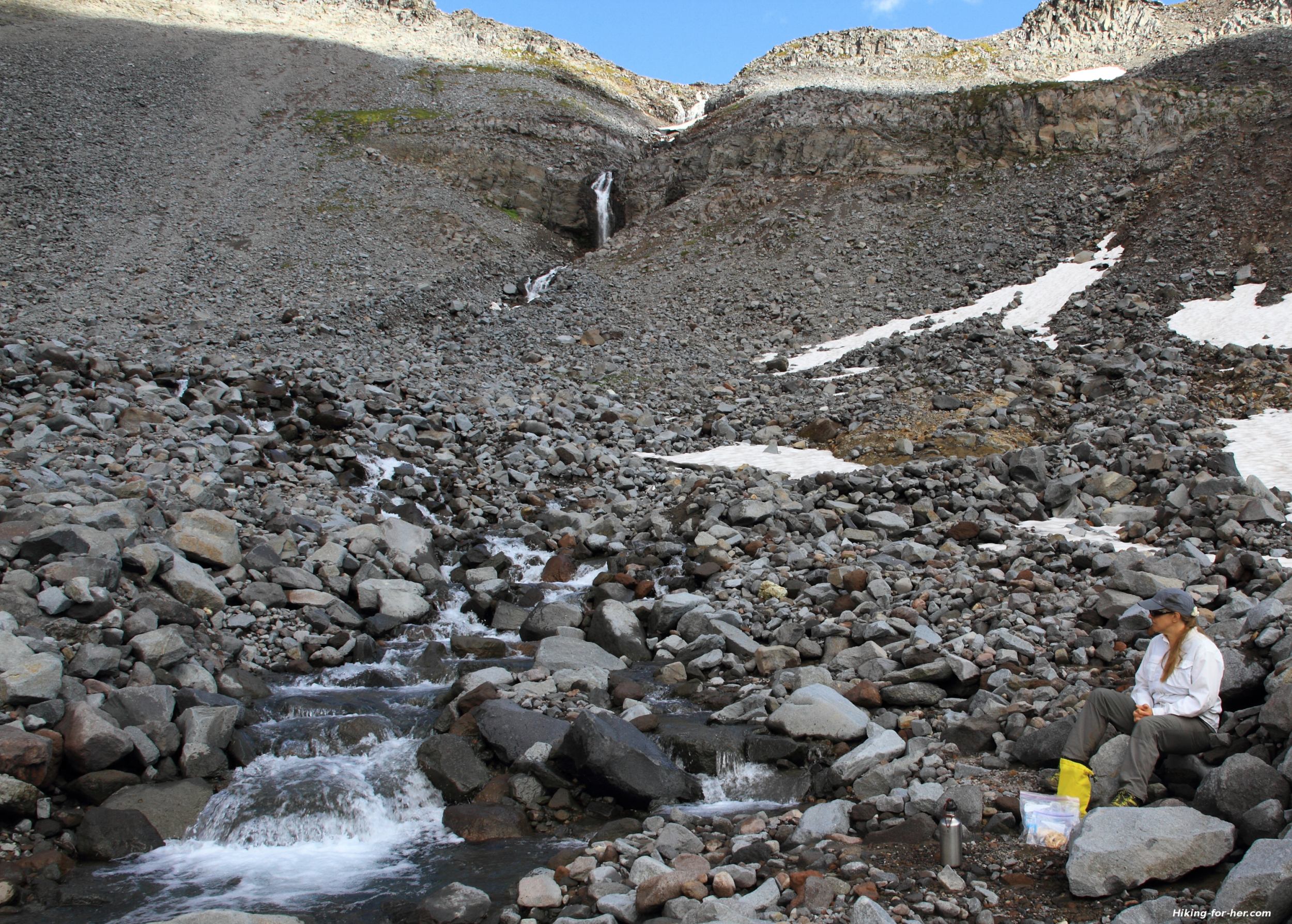 Hiker resting near a boulder filled stream