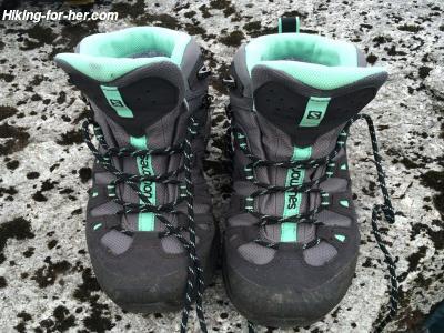 Unlaced grey and blue hiking boots on rocks Unlaced grey and blue hiking boots on rocks