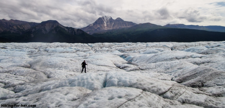 Hiker striding across surface of Nizina Glacier, Alaska