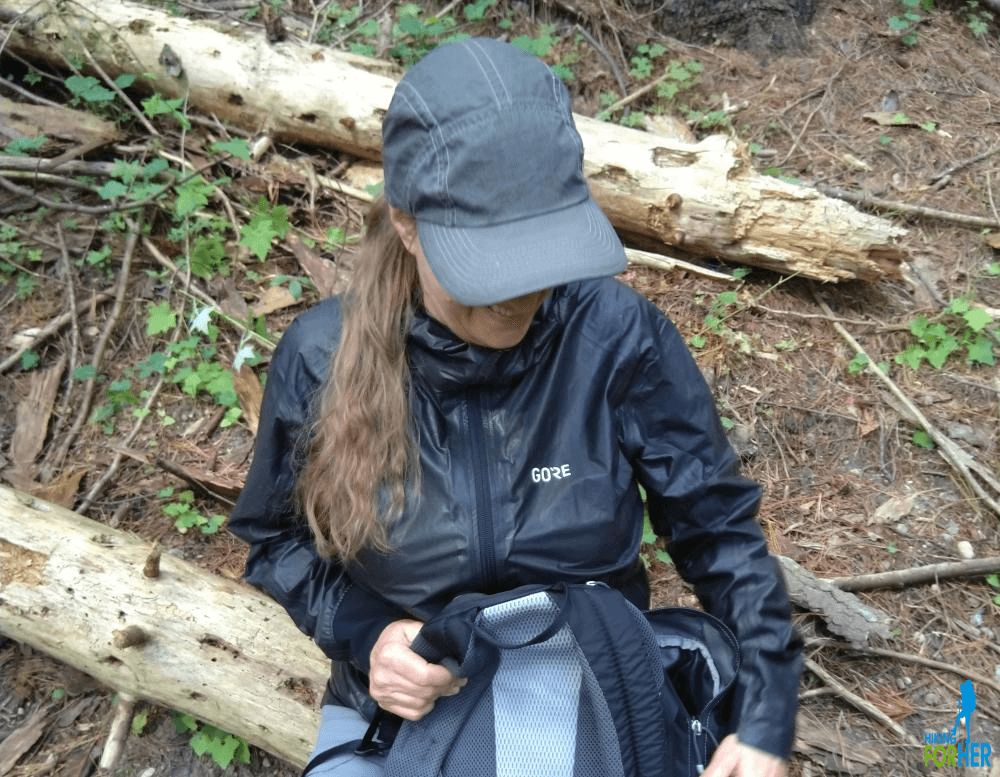Female hiker with backpack sitting on log along trail Female hiker with backpack sitting on log along trail