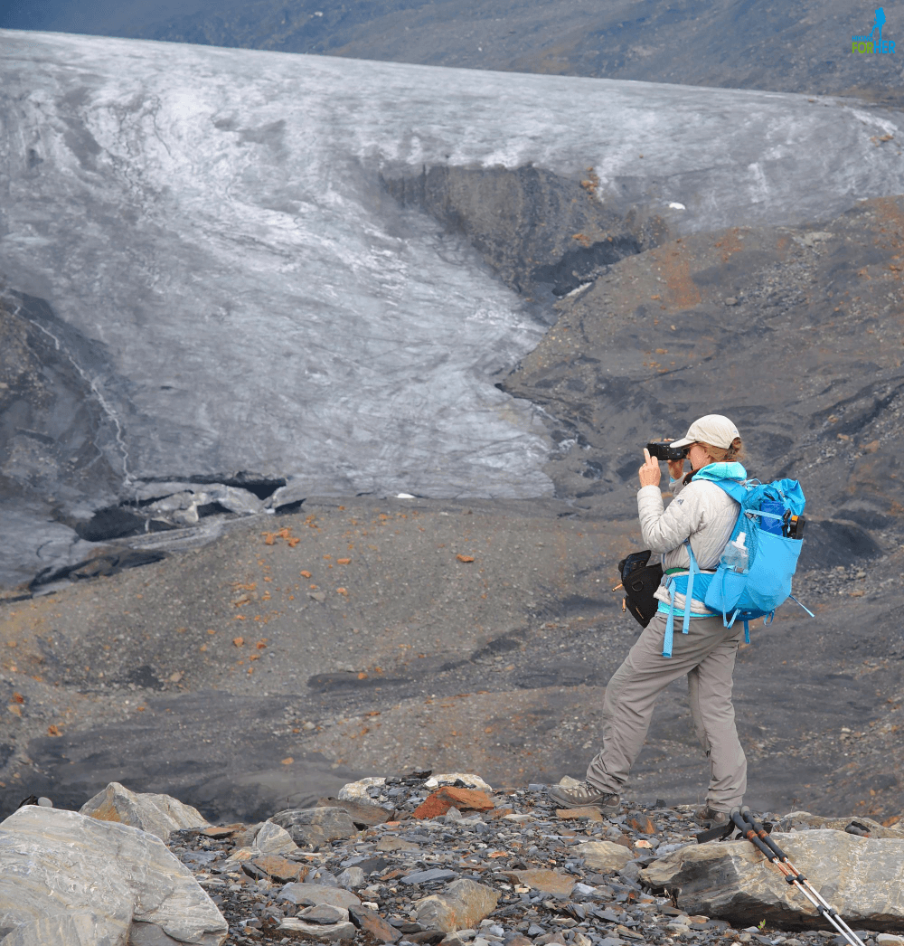 Female hiker taking a photograph, wearing technical hiking clothing and backpack Female hiker taking a photograph, wearing technical hiking clothing and backpack