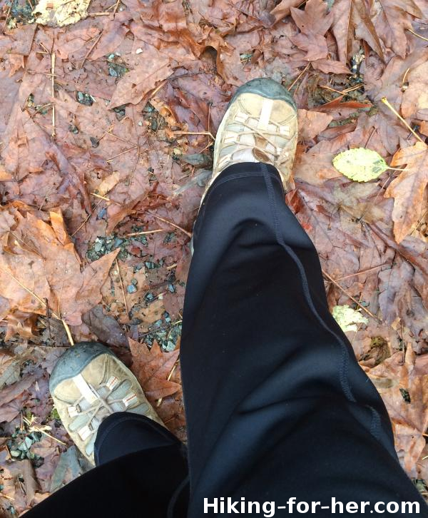 Hiking feet in trail shoes on leaf strewn wet trail Hiking feet in trail shoes on leaf strewn wet trail