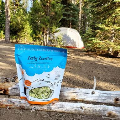 Packet of Zesty Zoodles on a log at a campsite Packet of Zesty Zoodles on a log at a campsite