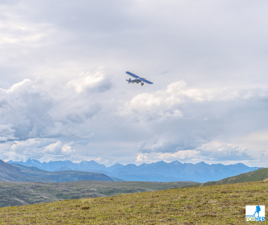 Supercub plane banking to land on a high alpine plateau in Alaska