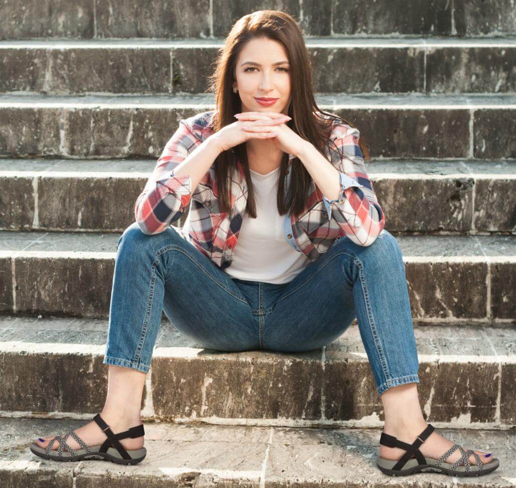 Female in jeans and plaid shirt showing off a pair of sandals on her feet Female in jeans and plaid shirt showing off a pair of sandals on her feet